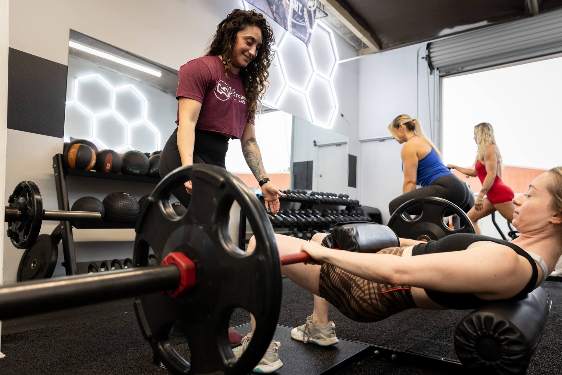 A Performance Lab coach spotting a client on a hip thrust while other women train in the Westlake Village studio