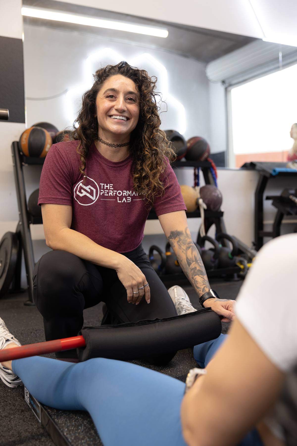 A Performance Lab coach smiling while coaching a client through a floor strength exercise